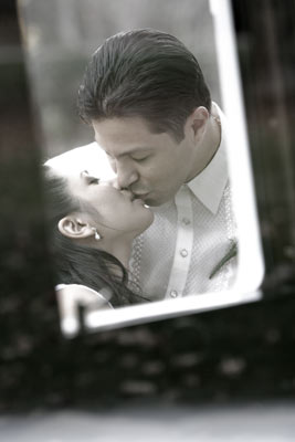 Magazine style fashion photoshoot in Orange County. Portrait of the Bride and Groom after the ceremony. This shot shows a kiss through the window of a classic car limousine. The bride is in her wedding dress with veil and bouquet.