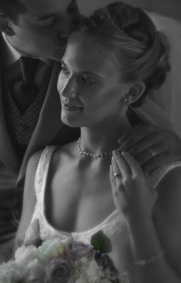 Magazine style fashion photoshoot in Santa Barbara. Portrait of the Bride getting a kiss by the groom in her wedding dress with wedding rings showing.