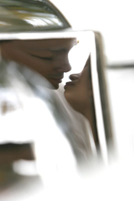 Magazine style fashion photoshoot in Santa Barbara. Portrait of the Bride and Groom photographed through a reflection on a classic car limousine.