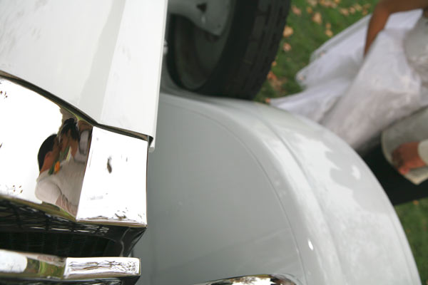 Magazine style fashion photoshoot in Santa Barbara. Portrait of the Bride and Groom photographed through a reflection on a classic car limousine.