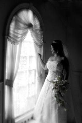 Magazine style fashion photoshoot in Santa Barbara. Portrait of the Bride gazing out the full sized window with bouquet in hand.